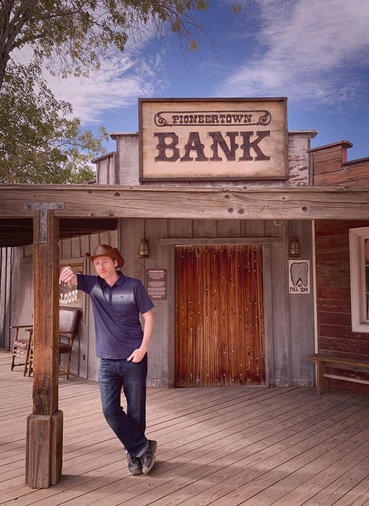 man in cowboy hat standing in front of old western bank of pioneertown in joshua tree